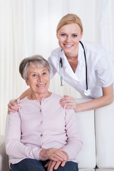 Portrait Of Young Doctor And Senior Patient Sitting On Couch