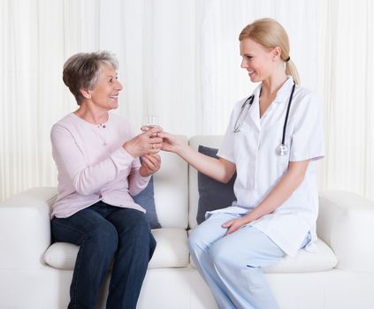 Portrait Of Young Doctor And Senior Patient Sitting On Couch