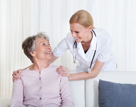 Portrait Of Young Doctor And Senior Patient Sitting On Couch