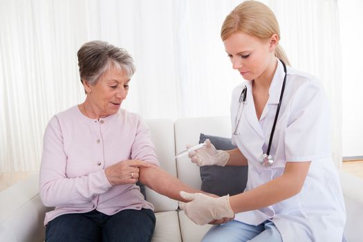 Young Female Doctor Injecting Vaccine To Senior Woman; Indoor