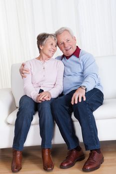 Portrait Of Happy Senior Couple Sitting On Couch