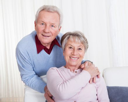 Portrait Of Happy Senior Couple Sitting On Couch