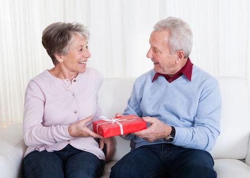 Senior Man Giving Gift To Senior Woman Indoors