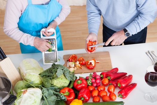 Happy Senior Couple Cutting Vegetables In Kitchen