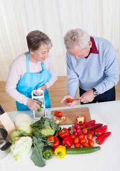 Happy Senior Couple Cutting Vegetables In Kitchen