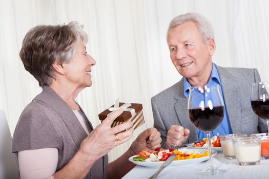 Senior Man Giving Gift To Senior Woman In Restaurant