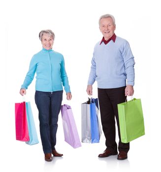 Portrait Of Happy Senior Couple Holding Shopping Bags