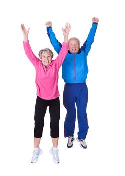 Portrait Of Senior Couple Jumping In Joy Over White Background