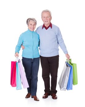 Portrait Of Happy Senior Couple Holding Shopping Bags