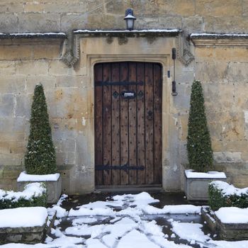 Pretty period property doorway with topiary box trees and snow, Broadway, Worcestershire, England.