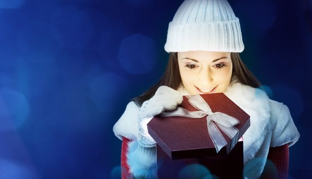 Happy young woman opening Christmas presents, copy space
