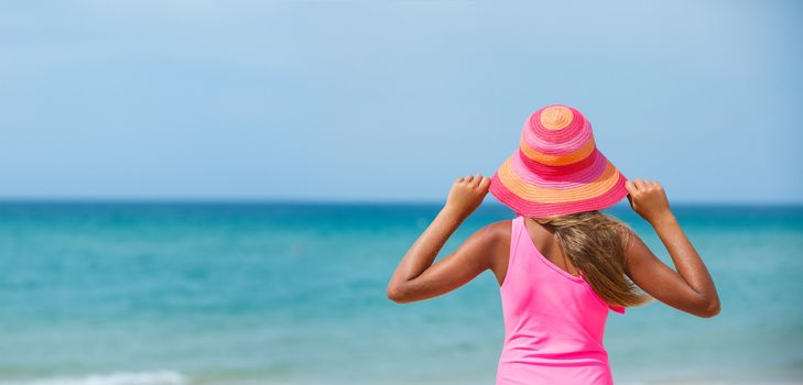 Back view of beautiful girl in pink hat and on background sea