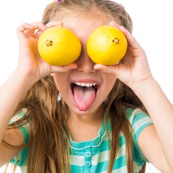 little girl with two lemons shows tongue isolated on white background
