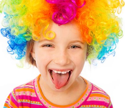 smiling little girl shows tongue in clown wig isolated on white background