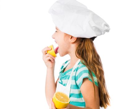 little girl in chef hat licks lemon on a white background