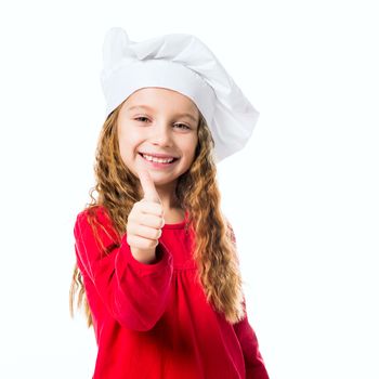 smiling little girl in chef hat with thumb up on white background