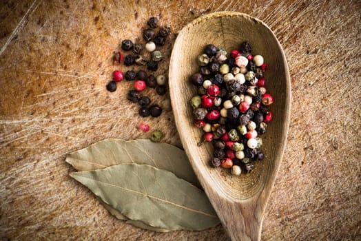 spices in a wooden spoon with laurel leaves on cutting board