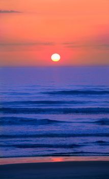 Beautiful, colorful sunset over the ocean shore with gentle waves