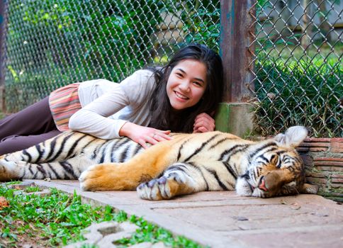 Biracial teen playing with sleeping tiger cub in Thailand