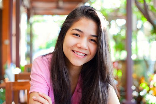 Biracial teen girl relaxing outdoors on sunny veranda