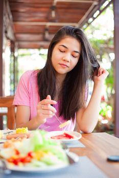 Biracial teen girl eating food outdoors on veranda