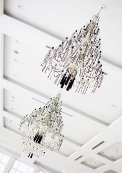 Two  beautiful crystal chandeliers hanging on white ceiling