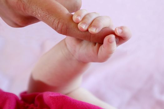 Cute baby hand holding on to it's mothers finger