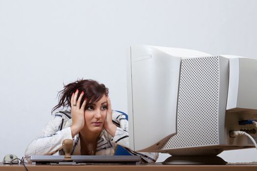 Young female clerk is helplessly looking at computer monitor