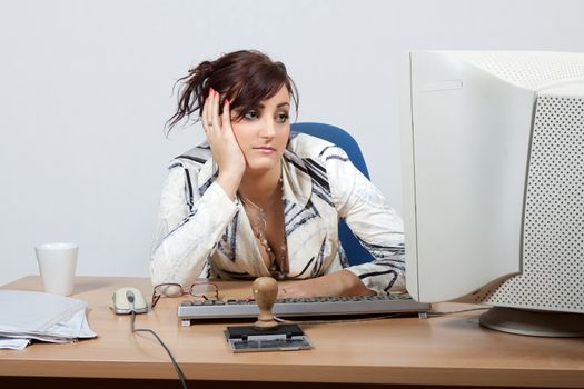 Young female office worker bored looking at a computer monitor