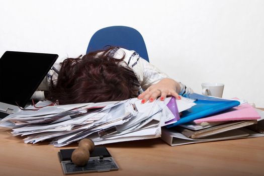 Young female office worker sleep at a desk with a pile of papers