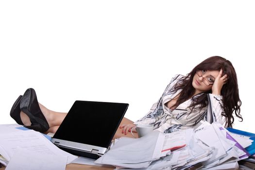 Young female office worker sitting with feet on desk with a pile of papers and looks tired and bored