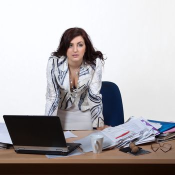 Young female office worker standing behind a desk with a stern look