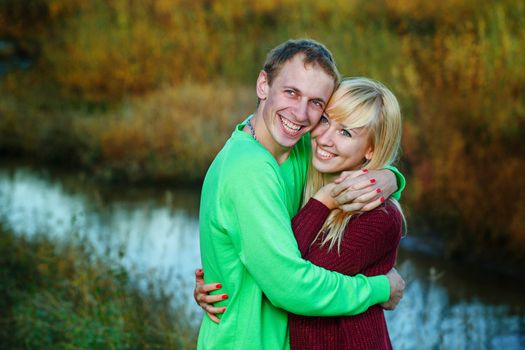 Young couple tenderly and lovingly embrace each other on banks of river