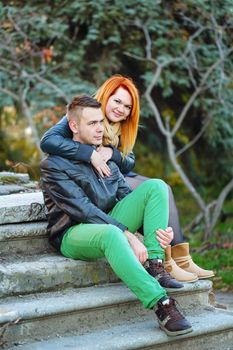 Attractive young couple sitting on the steps and hugging each other