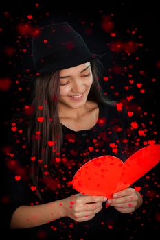 Beautiful girl reading a heart-shaped Valentine’s Day card.