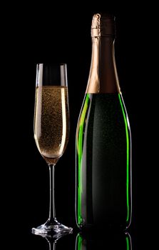Glass and bottle of champagne on black background