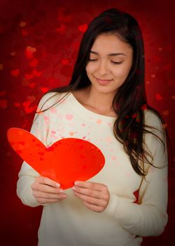 Beautiful girl reading a heart-shaped Valentine’s Day card.