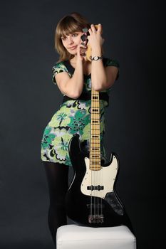 Young beautiful girl with a guitar on a dark background