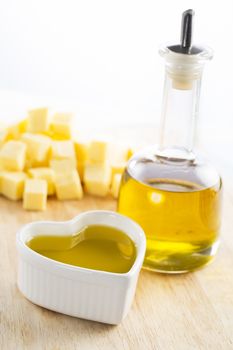 Olive oil in bottle and in a heart with butter in the background