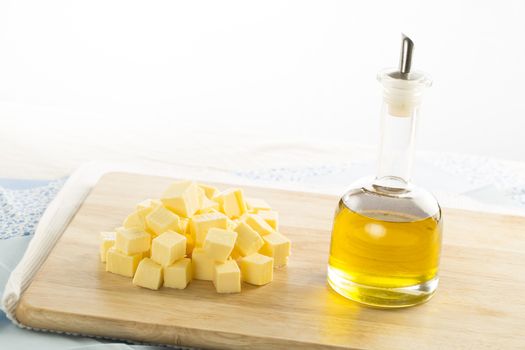 Olive oil in bottle and butter cubes on food preparation surface.