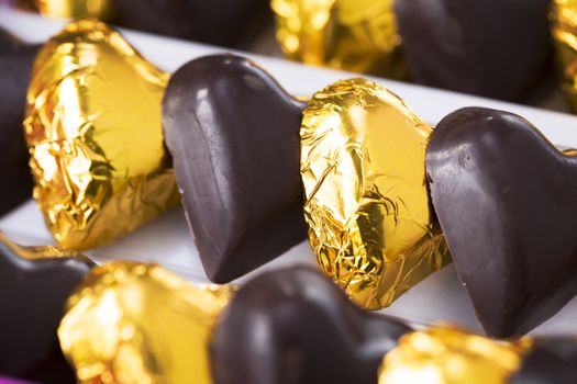 Chocolate hearts, some wrapped in gold foil, close up