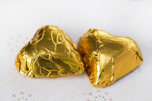 Chocolate candy hearts wrapped in gold foil, close up