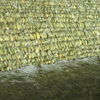 Cascade of water over green pebbles