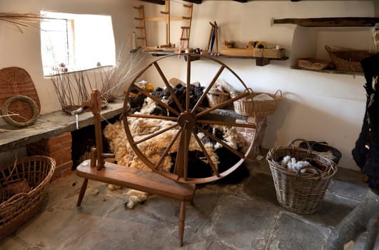 Traditional workshop with spinning wheel, fleece and baskets, England.