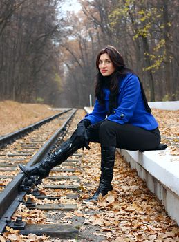 Young woman near the rails in the autumn forest