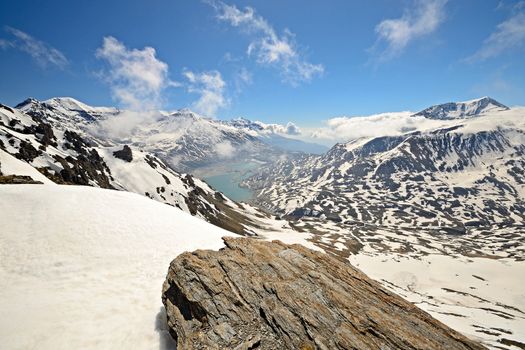 Superb wide angle view of snowcapped high mountain range from the top. On the left the artificial lake (and dam) of Mont Cenis, France