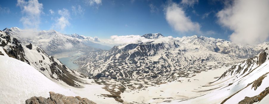 Superb wide angle view of snowcapped high mountain range from the top. On the left the artificial lake (and dam) of Mont Cenis, France