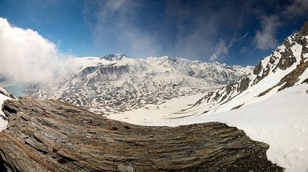 Superb wide angle view of snowcapped high mountain range from the top. On the left the artificial lake (and dam) of Mont Cenis, France