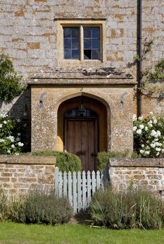 Stone farmhouse doorway with white roses, and garden gate.