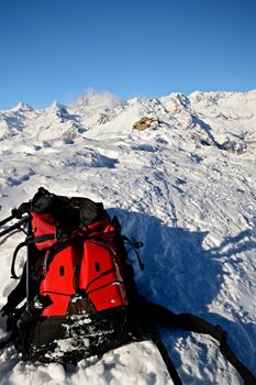 On the top of the mountain, pair of back country - tour ski and a backpack with avalanche safety tools. Scenic high mountain background (Gran Paradiso peak, 4061 m).